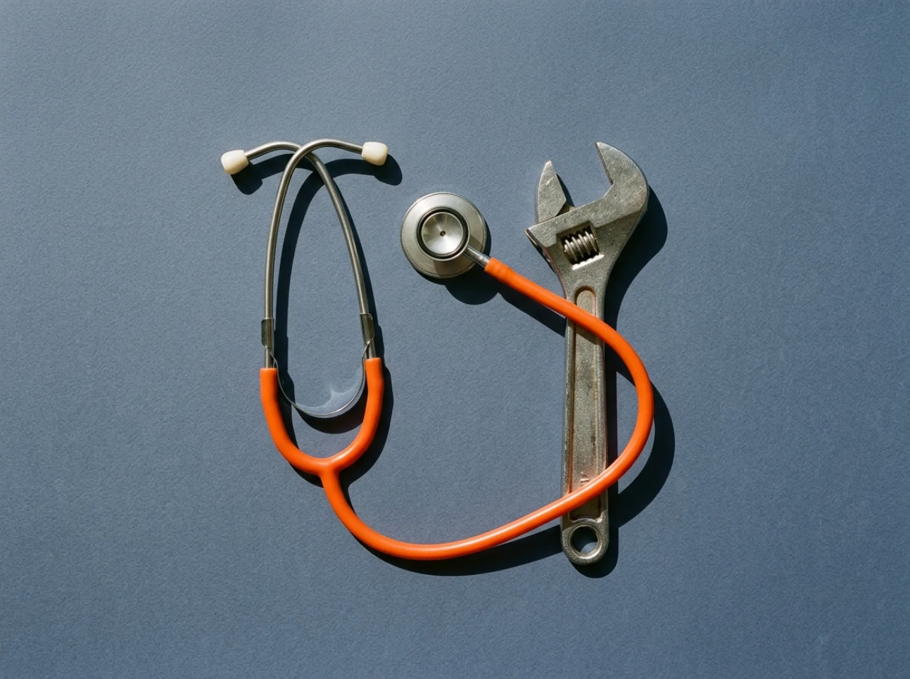 Stethoscope and wrench on slate paper