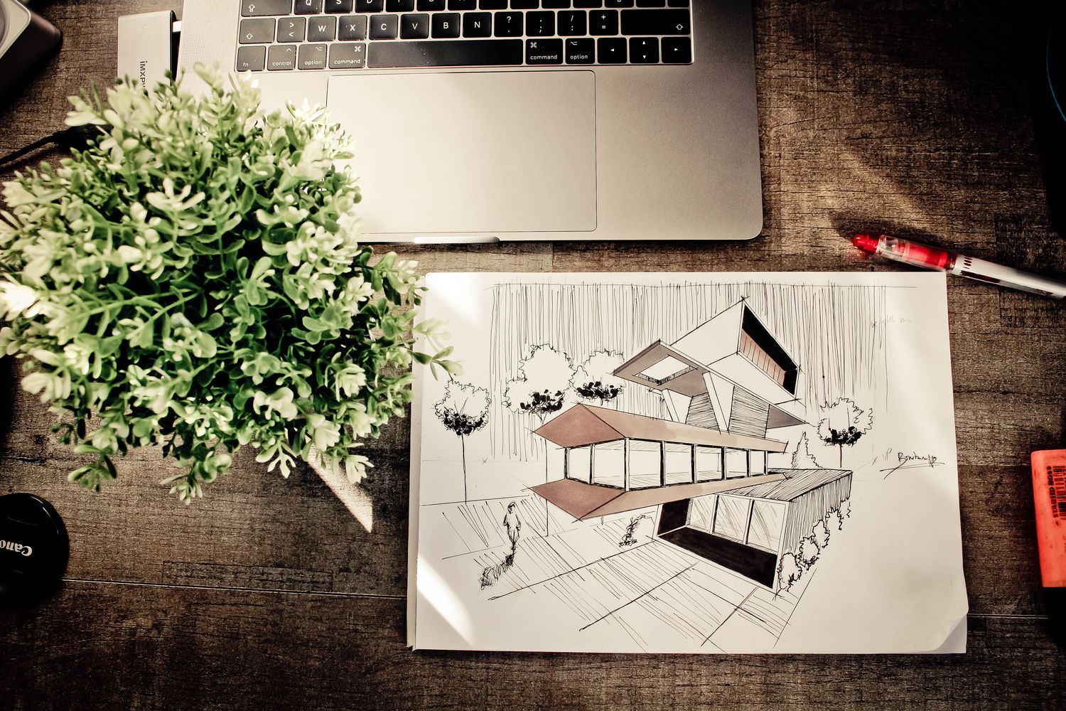 Architect's building sketch and laptop on a warm wooden desk