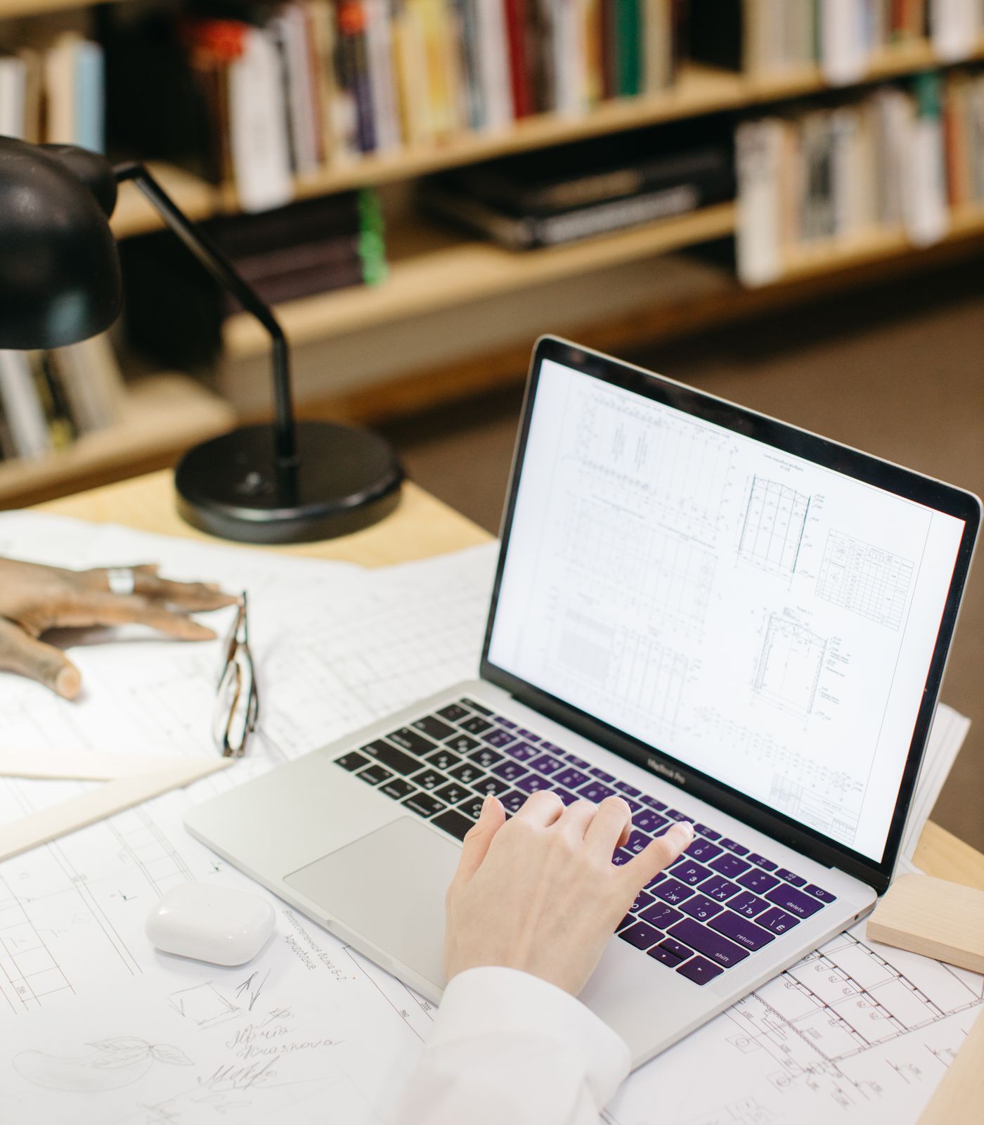 Operator working over architectural drawings in a book-lined study